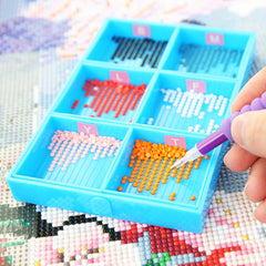Blue 6-slot diamond painting tray with color-coded sections and a purple drill pen picking up orange drills – ideal for efficient sorting and adult DIY crafts.