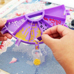 Purple tray in use showing drills separated in slots with pens, wax, brush, spoon, and finger protectors. Keeps drills visible and tidy, prevents mixing, and allows quick switching between colors, making diamond painting faster and more enjoyable.