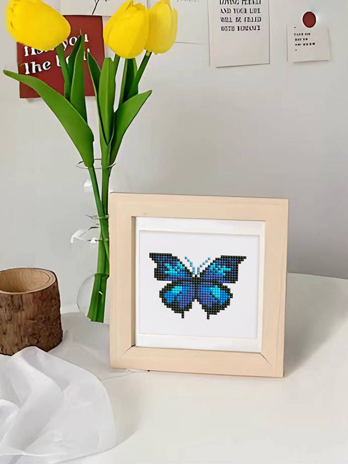 Framed blue butterfly mini diamond painting kit displayed on a desk with yellow tulips, perfect for home decor and butterfly diamond art lovers.