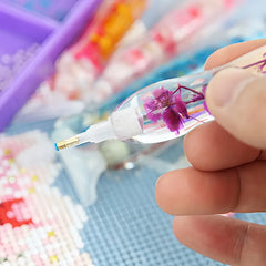 Diamond painting tool with purple flower pen being held for detail work – great for long sessions without hand fatigue.
