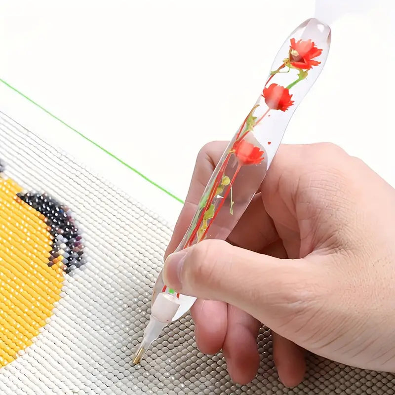 Diamond painting pen with red real flower body in use, placing drills on canvas – ideal for calm, focused DIY enthusiasts.