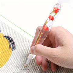 Diamond painting pen with red real flower body in use, placing drills on canvas – ideal for calm, focused DIY enthusiasts.