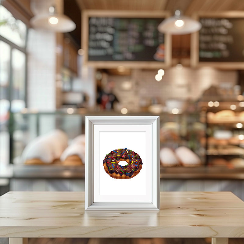 MIni Framed donut diamond painting placed on a wooden table in a cozy café interior.