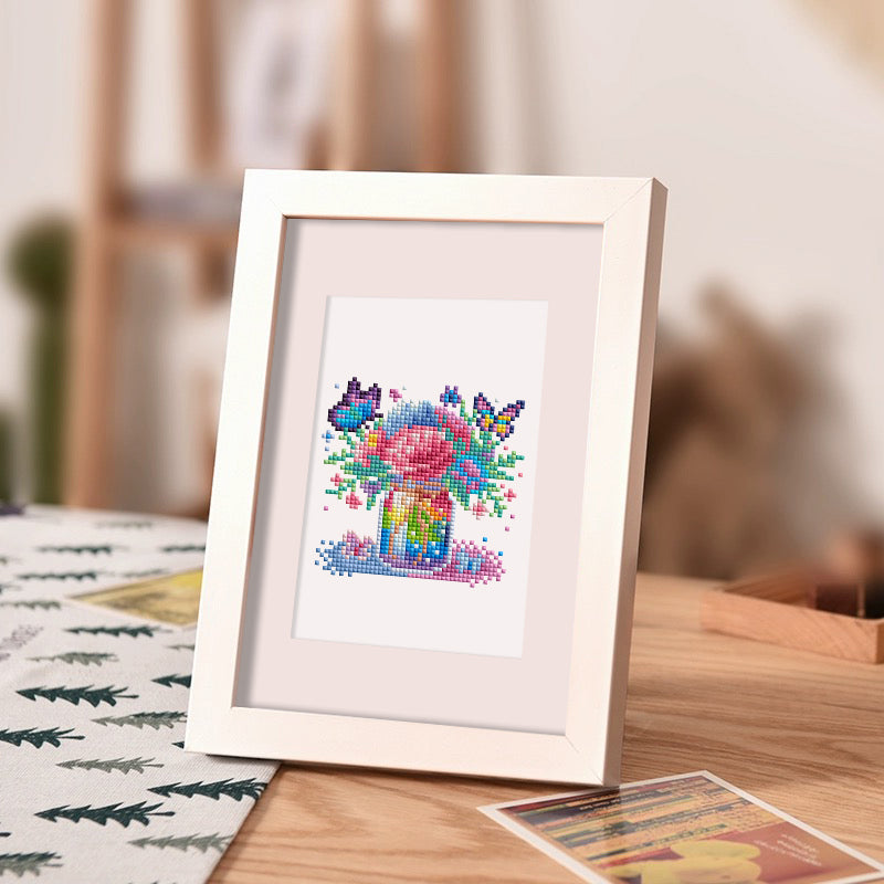 Framed vase diamond painting kit artwork displayed on a wooden desk, perfect as whimsical decor for children or cozy creative spaces.