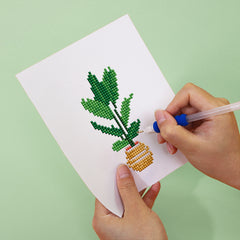 Hands placing drills on green plant canvas – beginner-friendly diamond painting for relaxation and focus