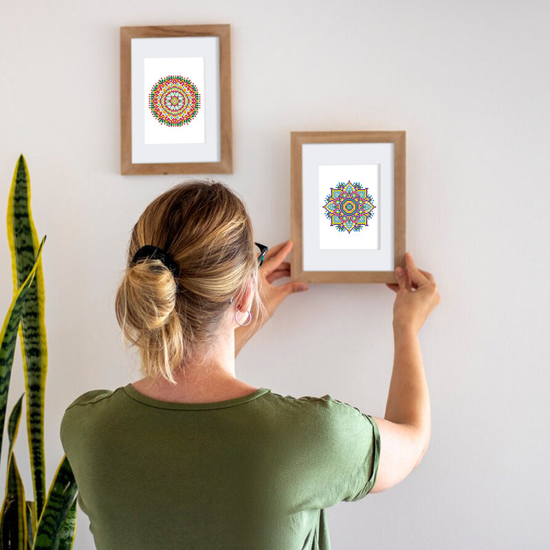 Woman hanging framed mandala diamond painting on wall, easy DIY decoration project