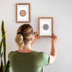 Woman hanging framed mandala diamond painting on wall, easy DIY decoration project