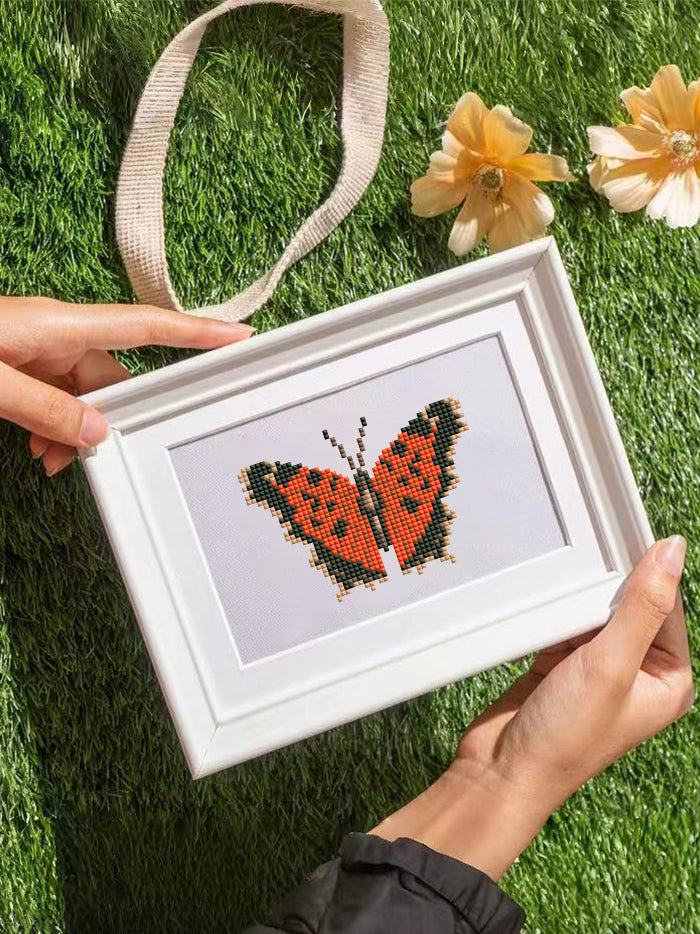 Hand holding framed brown butterfly diamond painting from Mini Butterfly Kingdom 2 – a charming addition to creative wall decor.