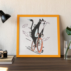 Framed small diamond painting of a funny cat on a bike, ideal for humorous desktop decoration or gifting.