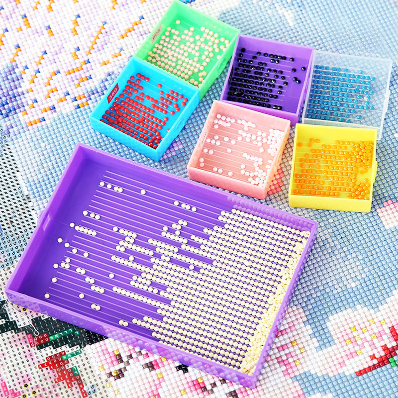 Diamond painting setup with 1 large purple tray and 6 small color trays filled with drills – great for organized, multi-color DIY art projects.