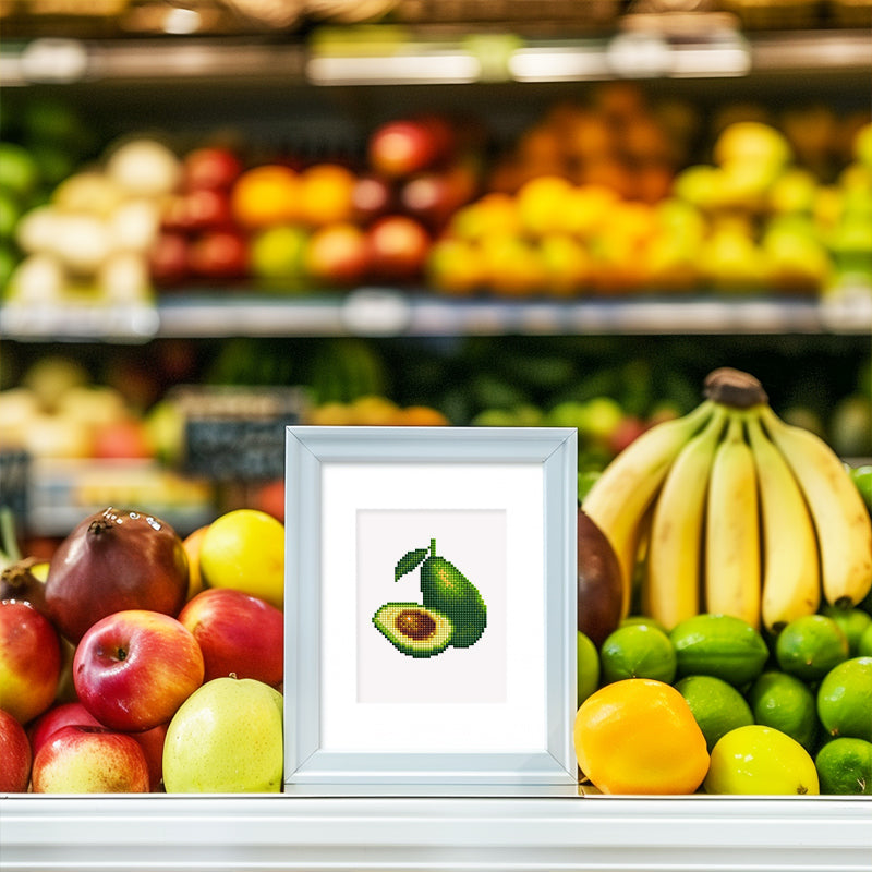 Framed avocado diamond painting displayed on a grocery fruit shelf, perfect for kitchen decor or fruit lovers.