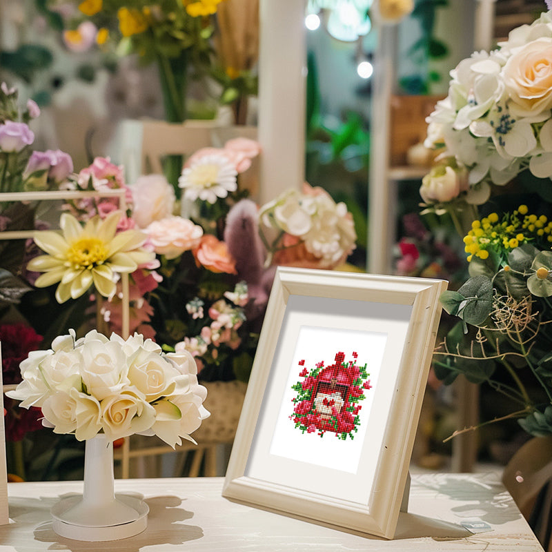Framed red rose bouquet diamond painting displayed among real flowers – showcasing soft canvas texture and romantic home décor potential.