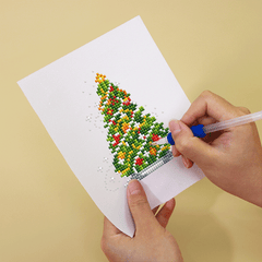 Diamond painting of a Christmas tree in progress on mini canvas. Compact and joyful design ideal for gifting and seasonal decorations.