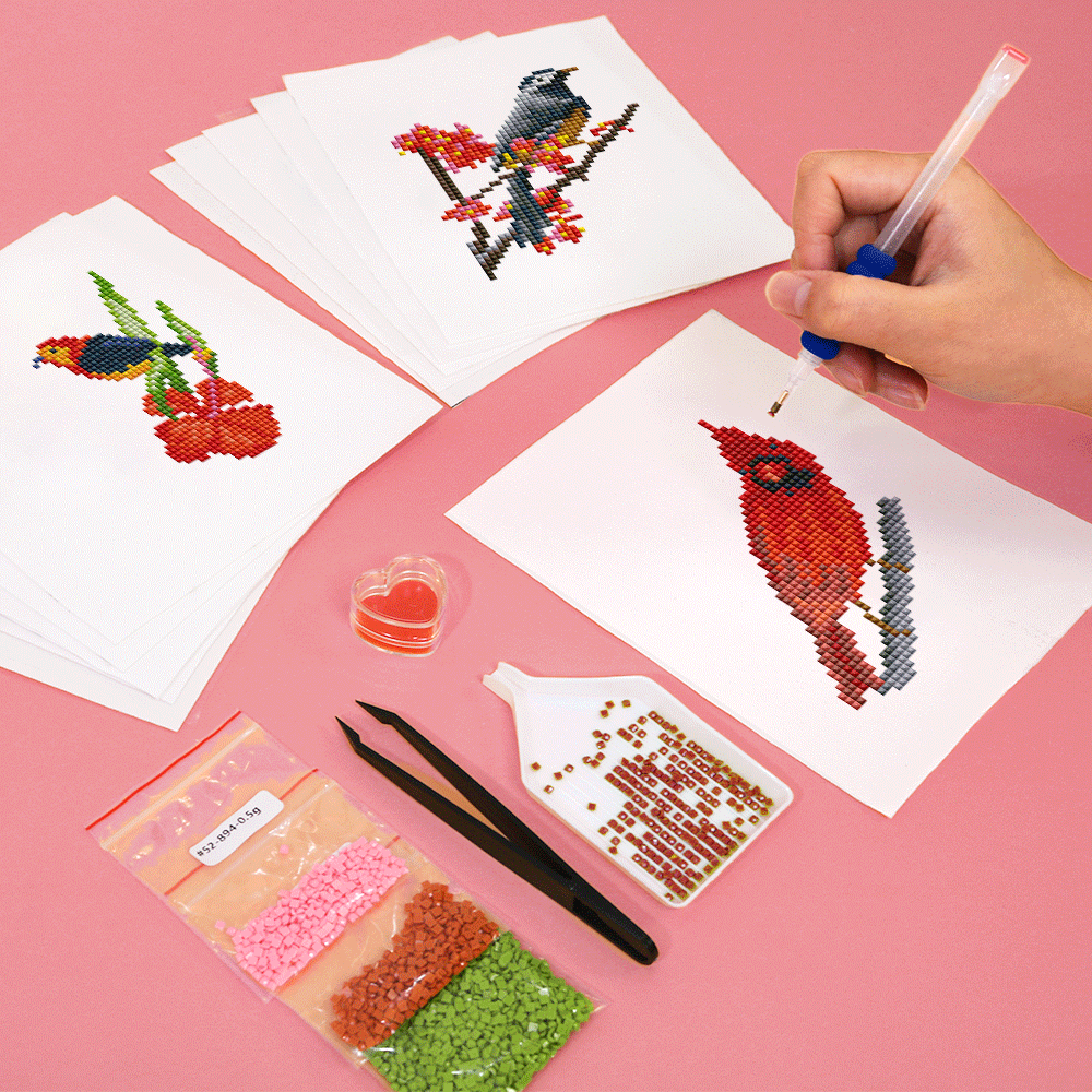 Close-up view of finished diamond painting with vibrant bird designs on white canvas.
