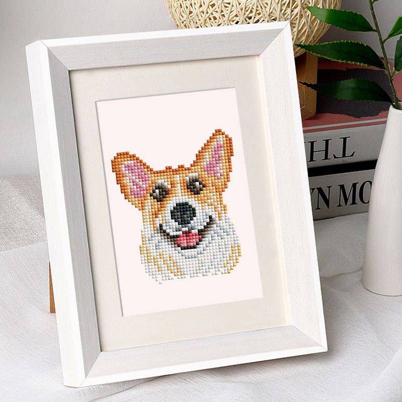 Diamond painting of a corgi dog framed and displayed on a white tabletop.