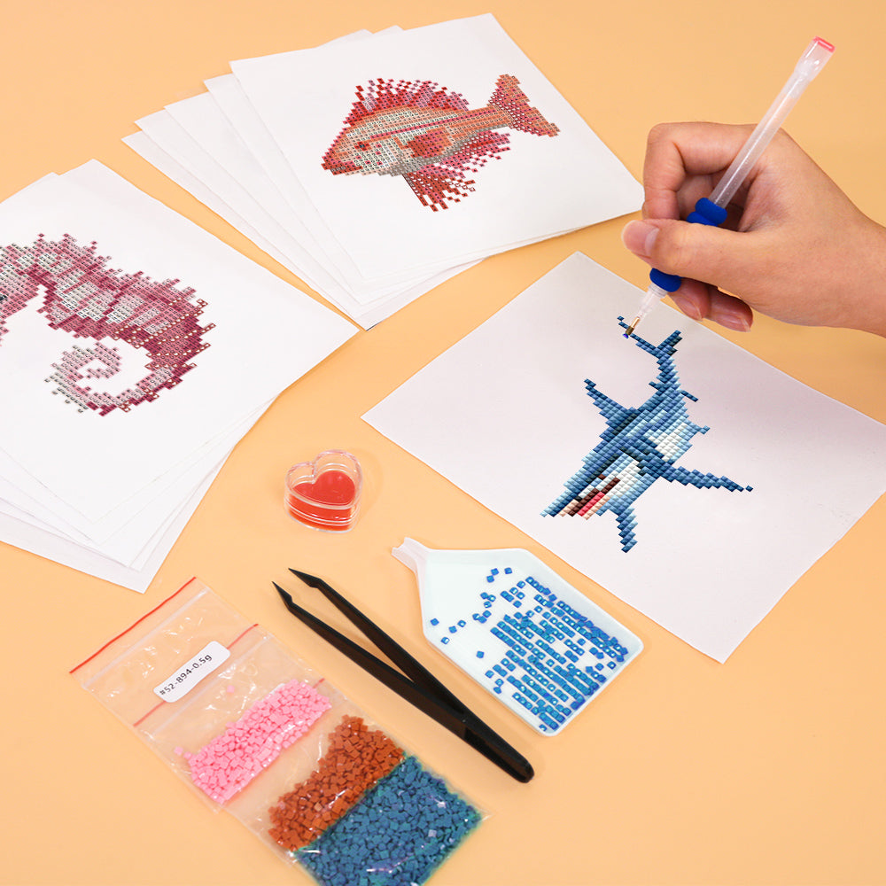 Hands placing drills on a fish diamond painting canvas from the Ocean shark DIY kit. Ideal for relaxing ocean-themed decor crafting. 