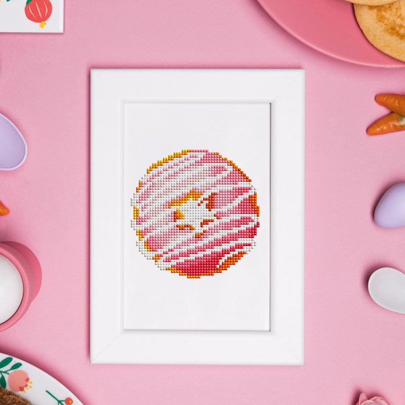 Colorful donut diamond painting framed on pink background with candy props, ideal for kitchen or cafe decoration.