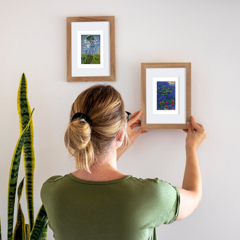 Woman hanging framed mini art diamond paintings on the wall – stylish and creative home decor idea.