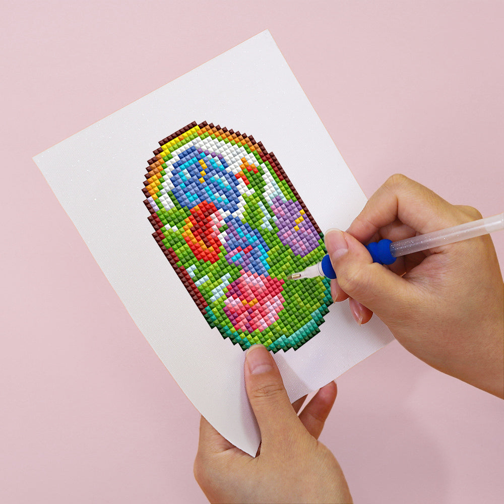 Hands working on arched stained glass window diamond painting in vibrant blue and red shades. A mindful DIY activity for all skill levels.