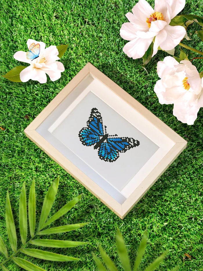 Blue butterfly diamond painting canvas styled with flowers and grass – a vibrant piece from the Mini Butterfly Kingdom 2 collection.