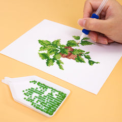 Hands placing colorful drills on a green leafy canvas—relaxing indoor craft for stress relief.
