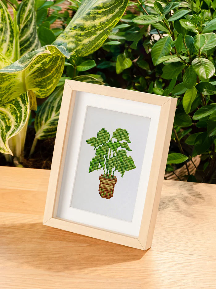 Finished green plant diamond painting framed on wooden stand—ideal for calming home or office decor.
