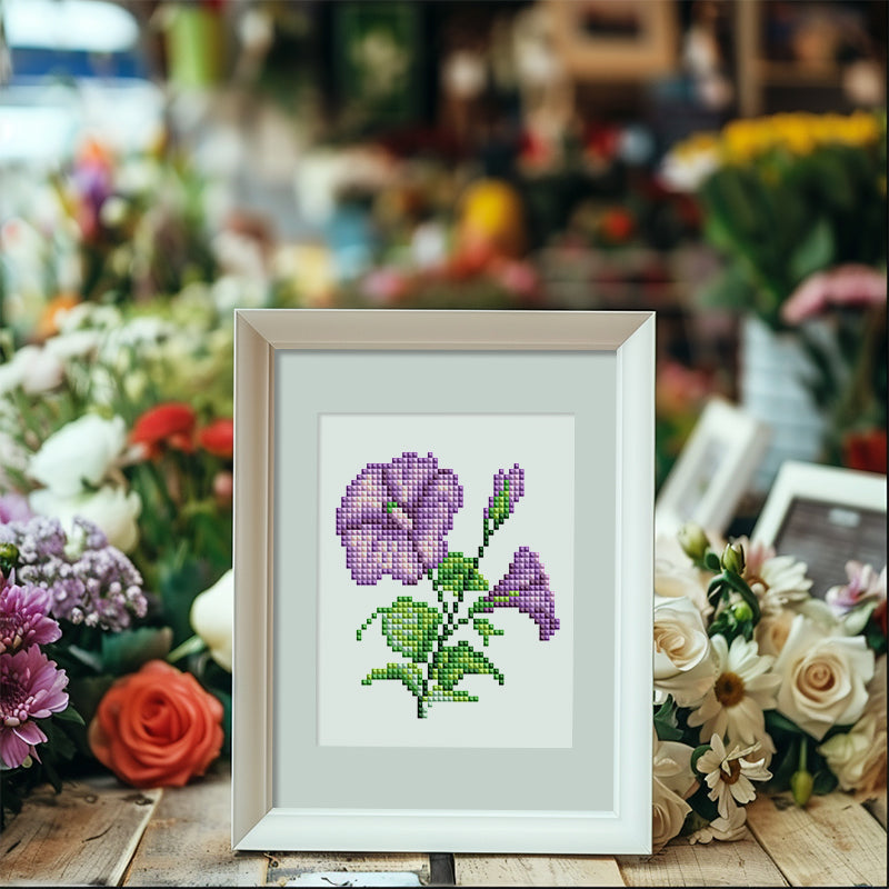 Purple flower diamond painting in a white frame displayed on a rustic table – beginner-friendly DIY floral art