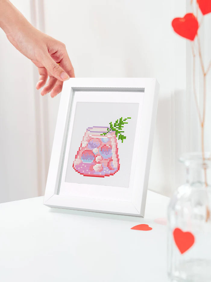 Diamond art of fruity cocktail in white frame held near window with hearts – perfect for gifts or summer.
